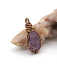 Side view of handcrafted raw ruby pendant showing artisan wire wrapping detail in antique bronze finish over copper