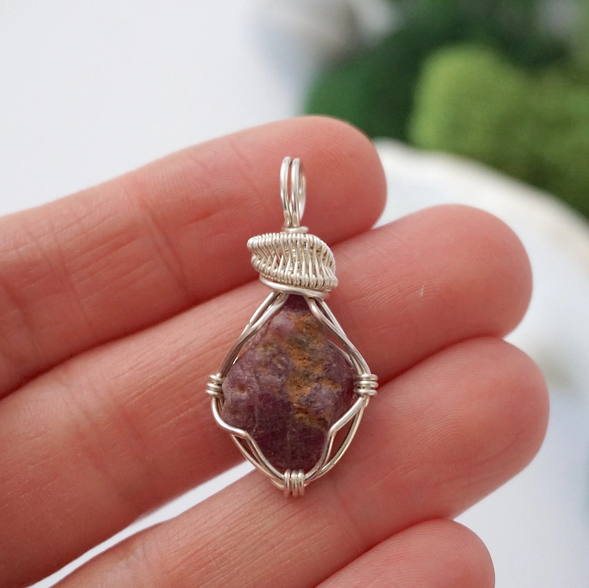 Raw ruby pendant held in hand to show size — natural ruby stone in silver wire wrapping, handmade crystal necklace for women