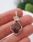 Raw ruby pendant held in hand to show size — natural ruby stone in silver wire wrapping, handmade crystal necklace for women