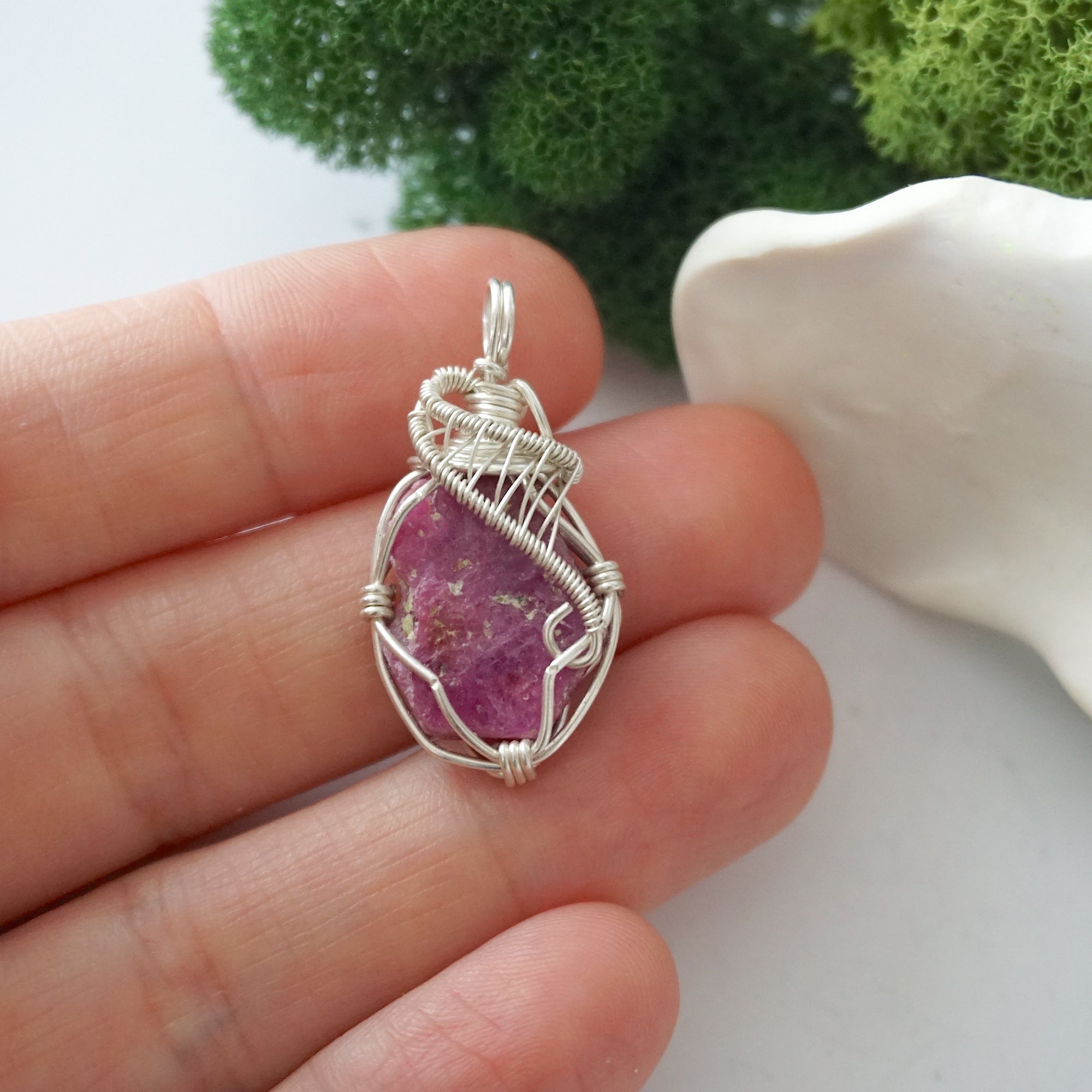 Handmade raw ruby pendant held in hand showing size — natural pink ruby stone wire wrapped in 925 sterling silver, approx. 1 inch, one of a kind