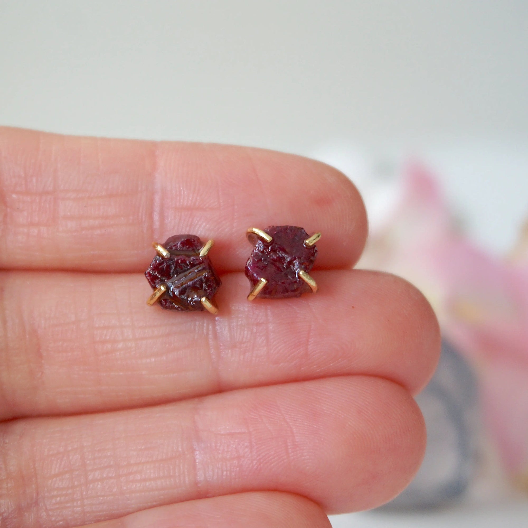 Raw ruby prong stud earrings held in hand to show size — genuine raw ruby in 14k gold vermeil setting, July birthstone earrings