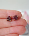 Raw ruby prong stud earrings held in hand to show size — genuine raw ruby in 14k gold vermeil setting, July birthstone earrings
