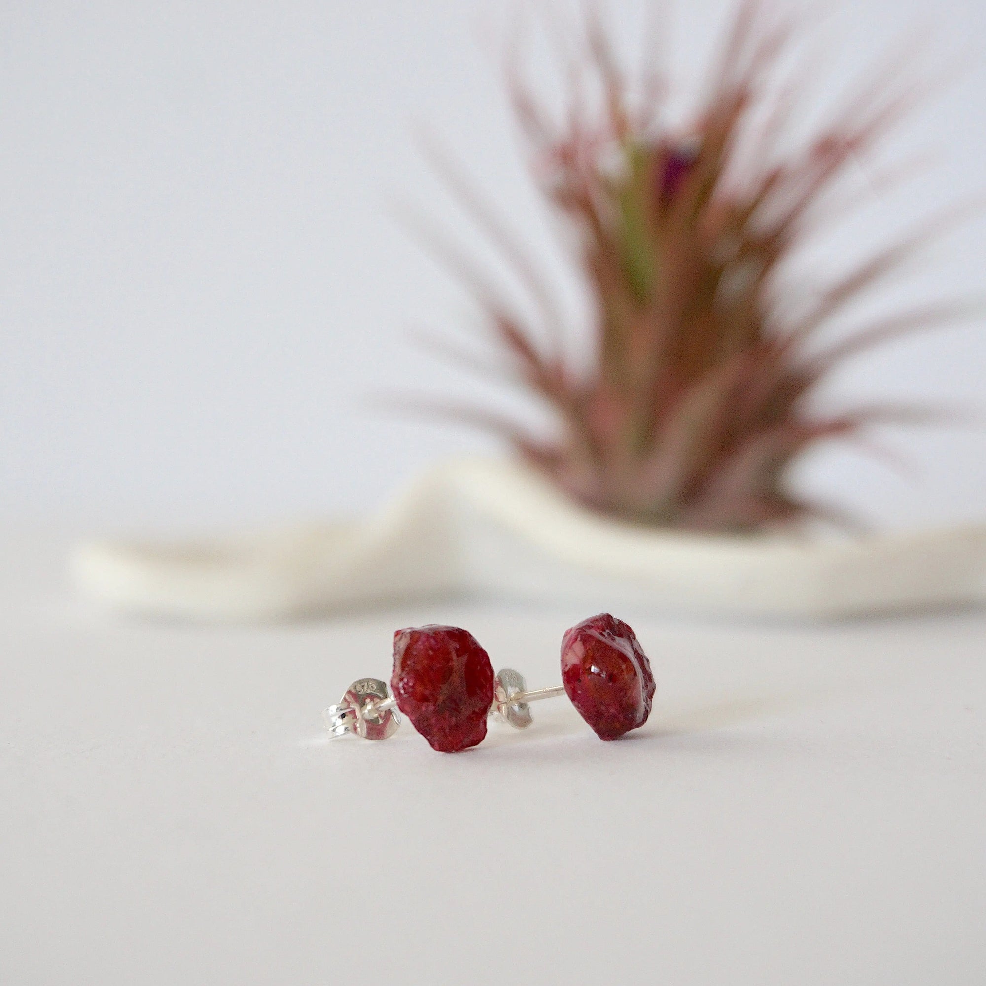 Side view of raw ruby stud earrings showing natural rough stone texture and sterling silver post — handmade gemstone earrings