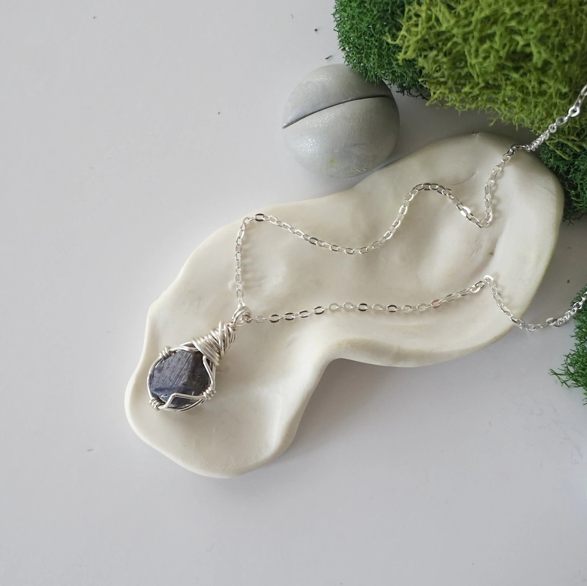 Simple raw sapphire necklace with silver plated brass chain laying flat