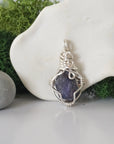 Back angle look at simple raw sapphire pendant with silver wire wrapping