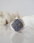 Back view of raw sapphire wire wrapped pendant — silver finish hand-wrapped setting shows craftsmanship and secure stone hold, handmade in Toronto Canada