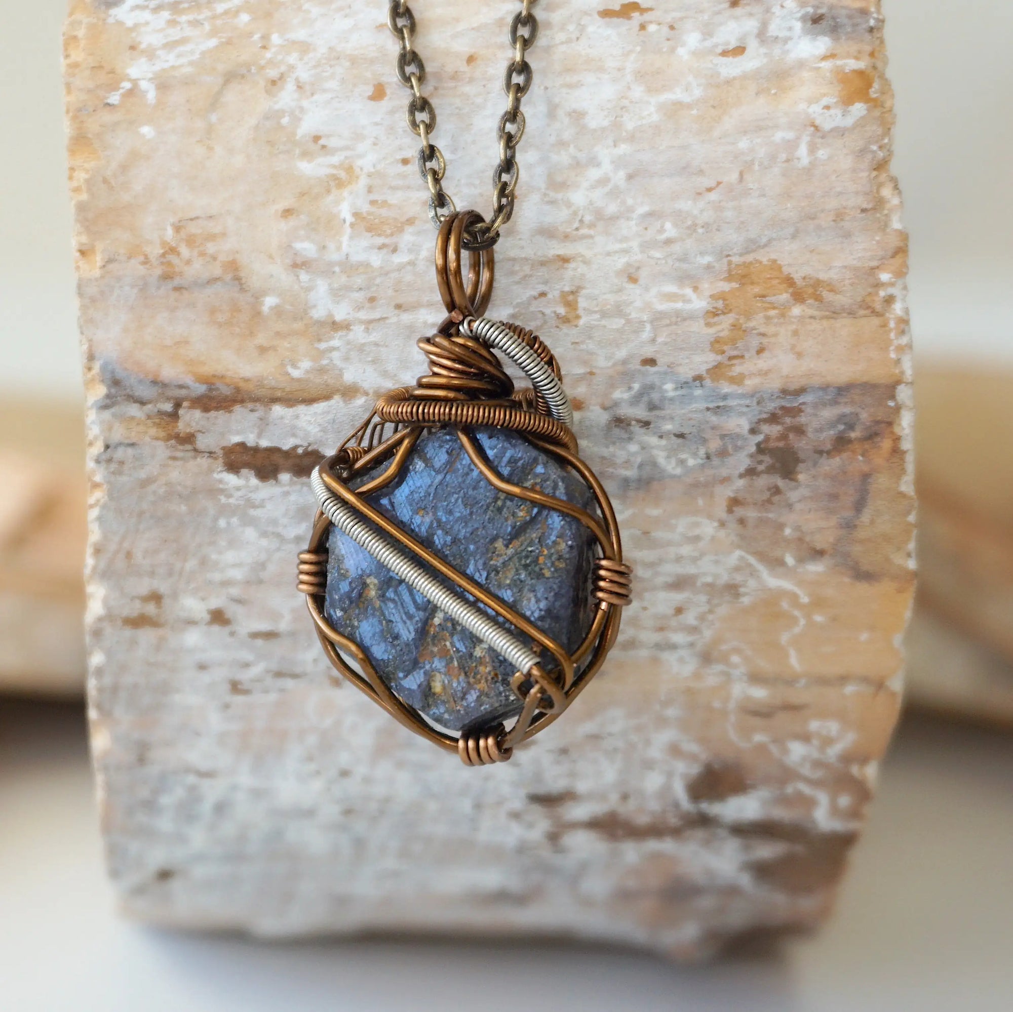 Back view of raw sapphire pendant showing the detail of antique bronze and dark silver wire-wrapping — one-of-a-kind artisan crystal jewelry