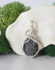 Front view of raw sapphire pendant — natural unpolished dark blue corundum stone hand-wrapped in detailed 925 sterling silver wire, handcrafted artisan jewelry