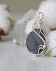 Left-angle close-up of raw sapphire pendant revealing the precision of 925 sterling silver wire-wrapping craftsmanship — women's artisan crystal jewelry