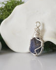 Detailed side angle view of simple raw sapphire pendant in silver wire