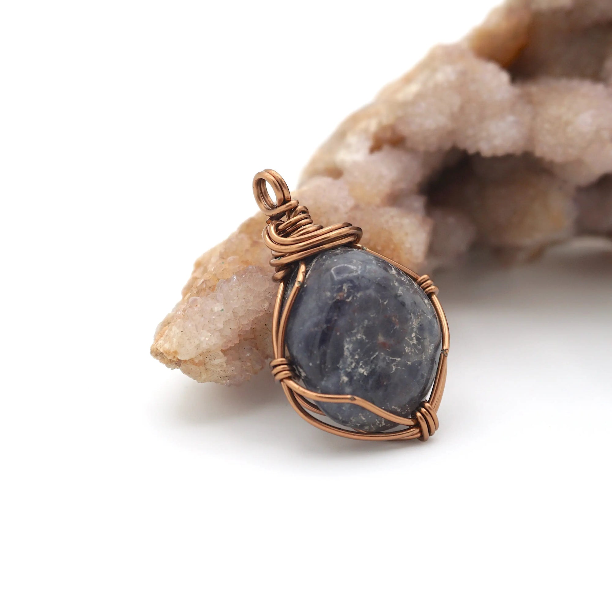 Right-angle detail of raw sapphire pendant showing artisan wire-wrapping technique in antique bronze — handcrafted crystal jewelry