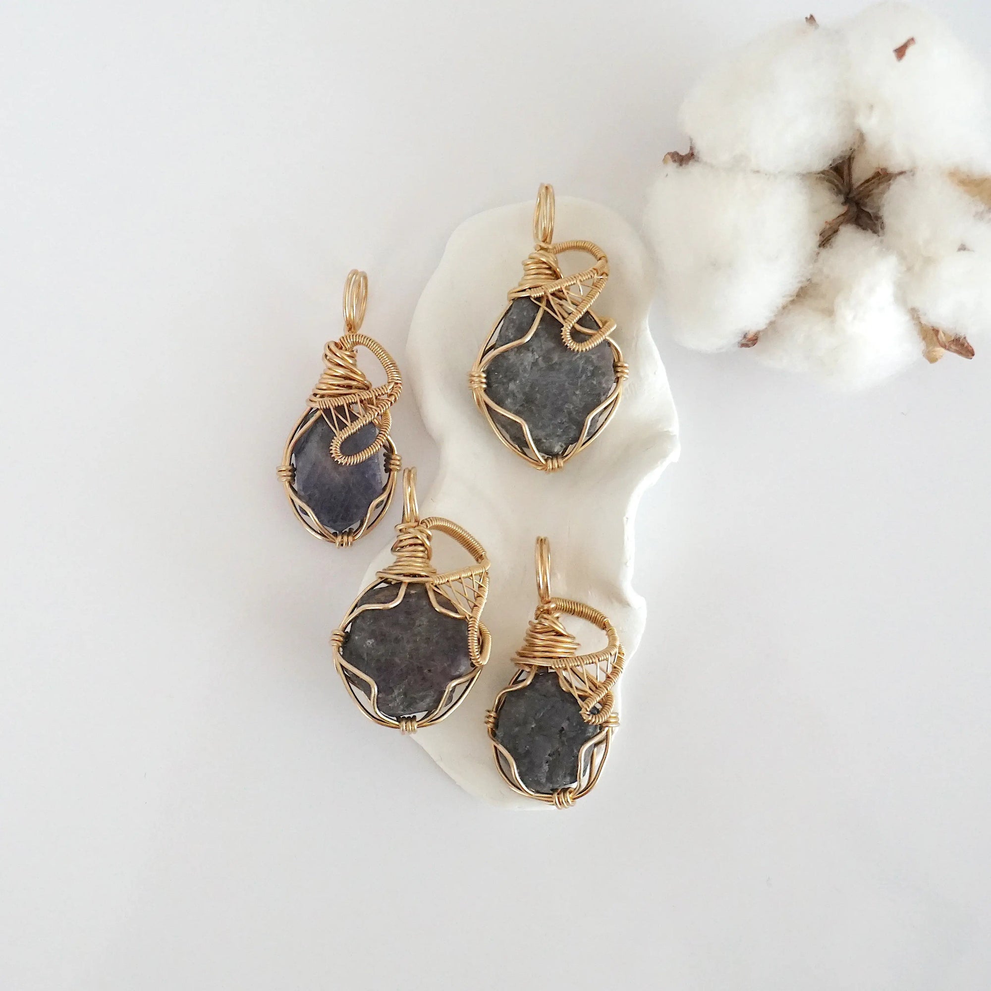 Four raw sapphire pendants in 14k gold filled, showing natural variation in size, shape, and color. Handcrafted September birthstone jewelry by Designs by Nature Gems.
