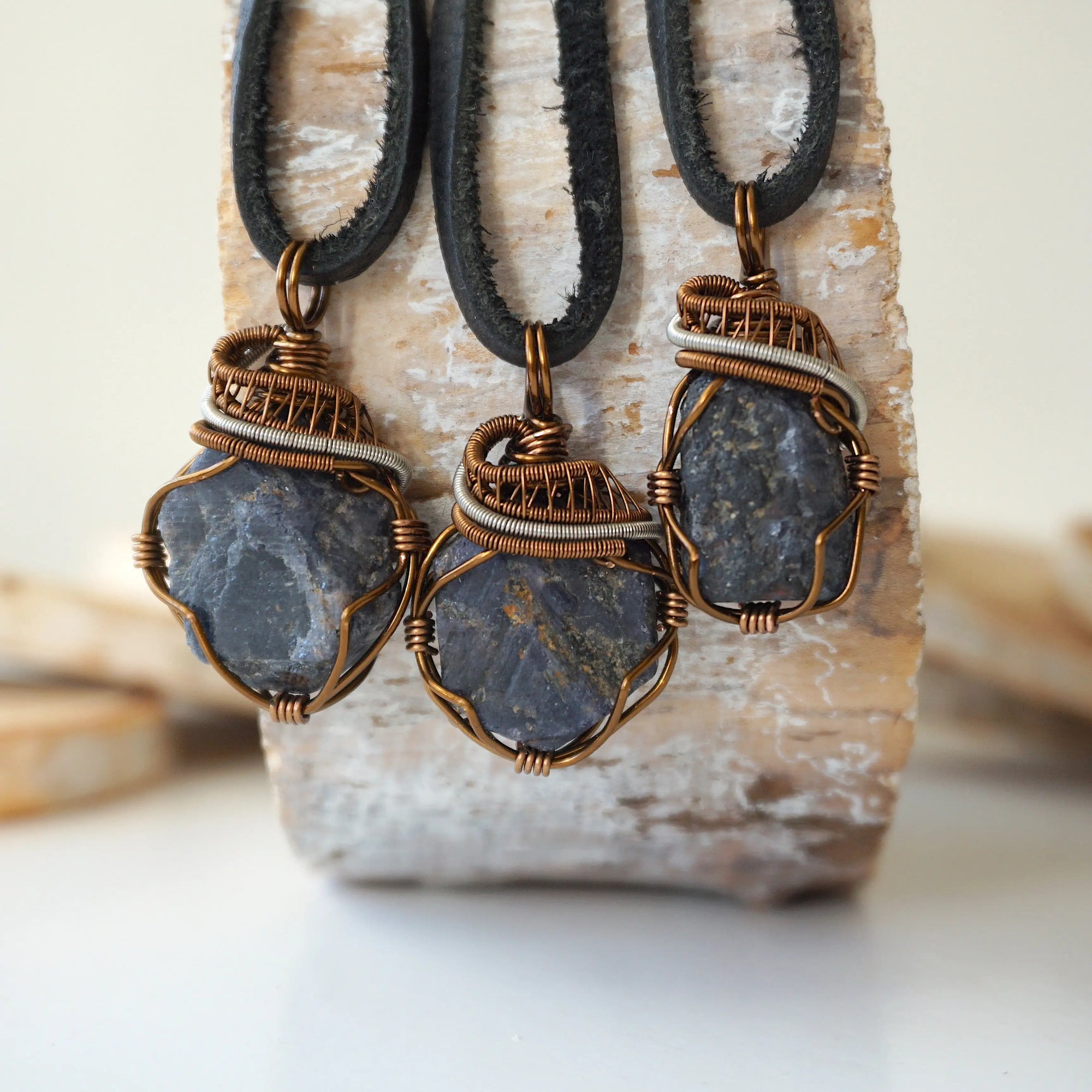 Three raw sapphire pendants showing natural variation in size, shape, and depth of colour — each men's wire-wrapped necklace is individually handcrafted and one of a kind