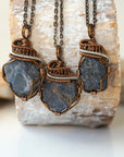Three raw sapphire pendants showing natural variation in size, shape, and depth of colour — each wire-wrapped antique bronze and dark silver necklace is individually handcrafted and one of a kind