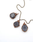 Three raw sapphire pendants showing natural variation in size, shape, and depth of colour — each wire-wrapped antique bronze necklace is one of a kind