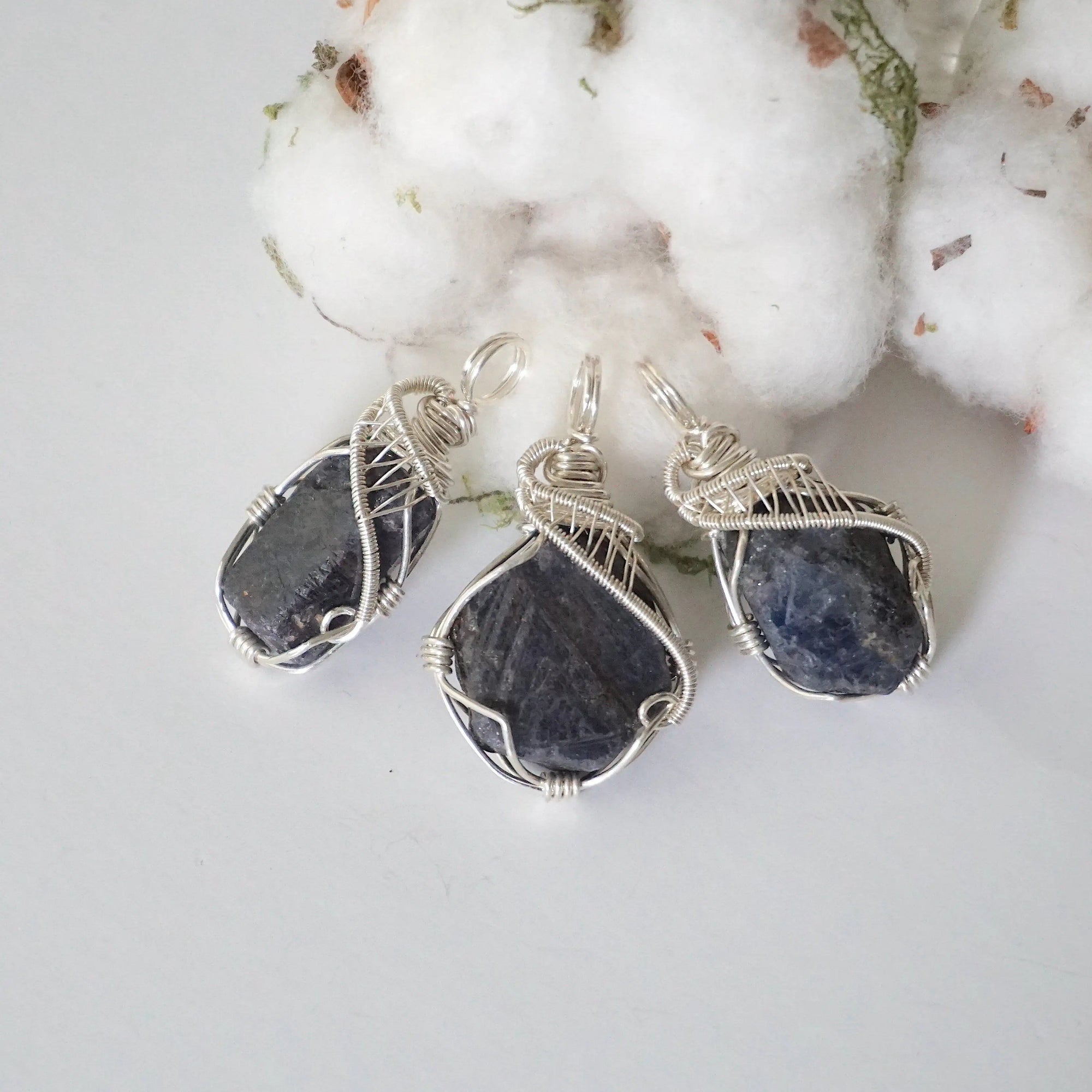 Three raw sapphire pendants showing natural variation in size, shape, and depth of colour — each women's 925 sterling silver wire-wrapped necklace is individually handcrafted and one of a kind