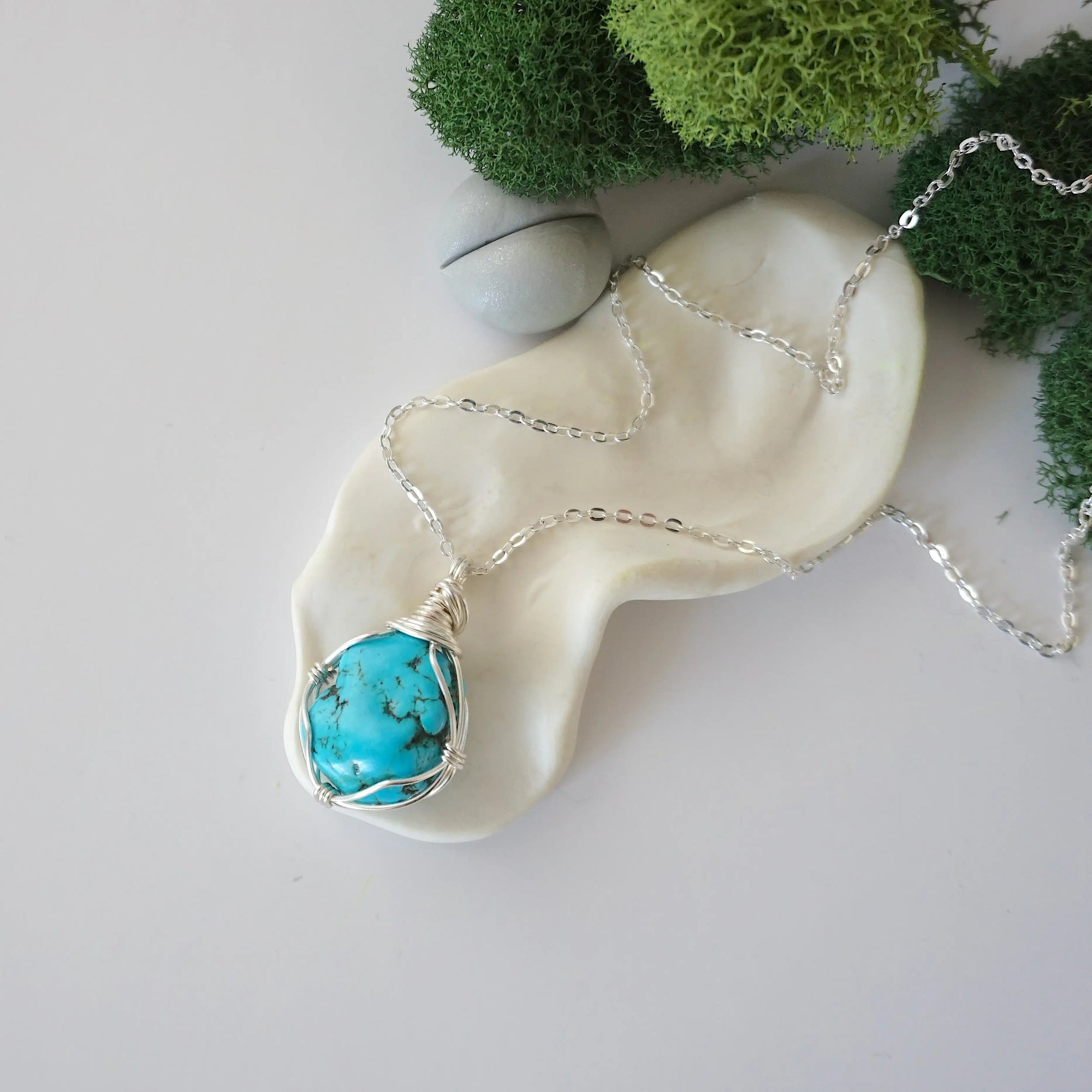 Raw turquoise necklace with simple silver wire wrapping on silver plated chain, minimalist crystal pendant flat lay