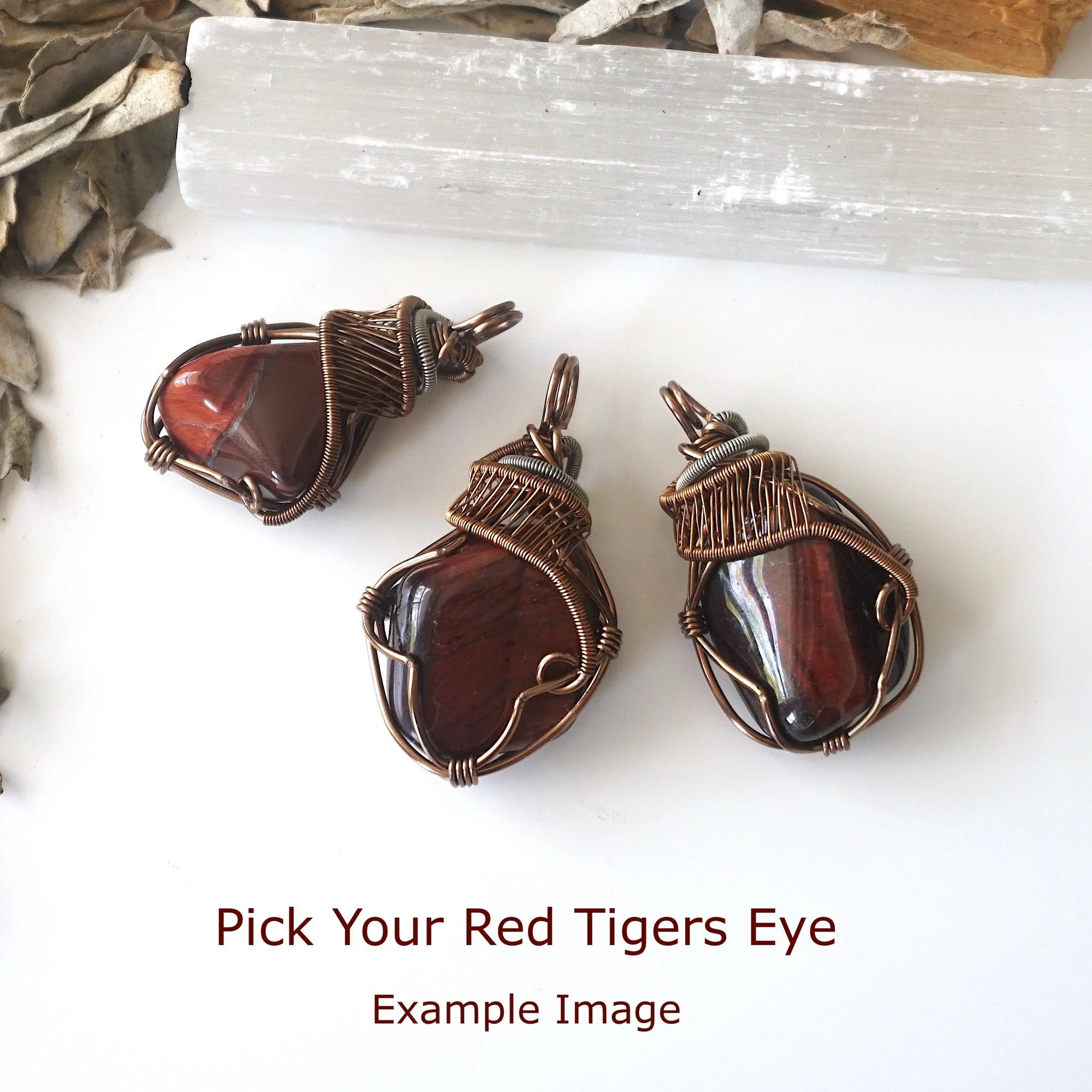 Three natural red tiger's eye pendants showing stone variation in size, shape, and color, artisan jewelry by Designs by Nature Gems.