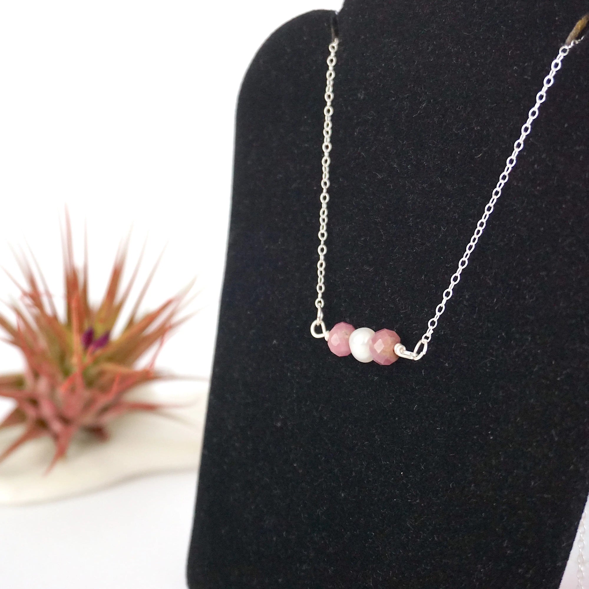 Left angle view of ruby and pearl bar necklace in 925 sterling silver on jewelry display