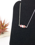 Left angle view of ruby and pearl bar necklace in 925 sterling silver on jewelry display