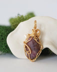 Back angle detail of ruby and freshwater pearl pendant, showing wire wrapping and natural stone
