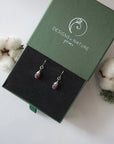 Ruby sterling silver drop earrings in branded Designs by Nature Gems jewelry box, showcasing handcrafted faceted ruby and sterling silver wire wrapping