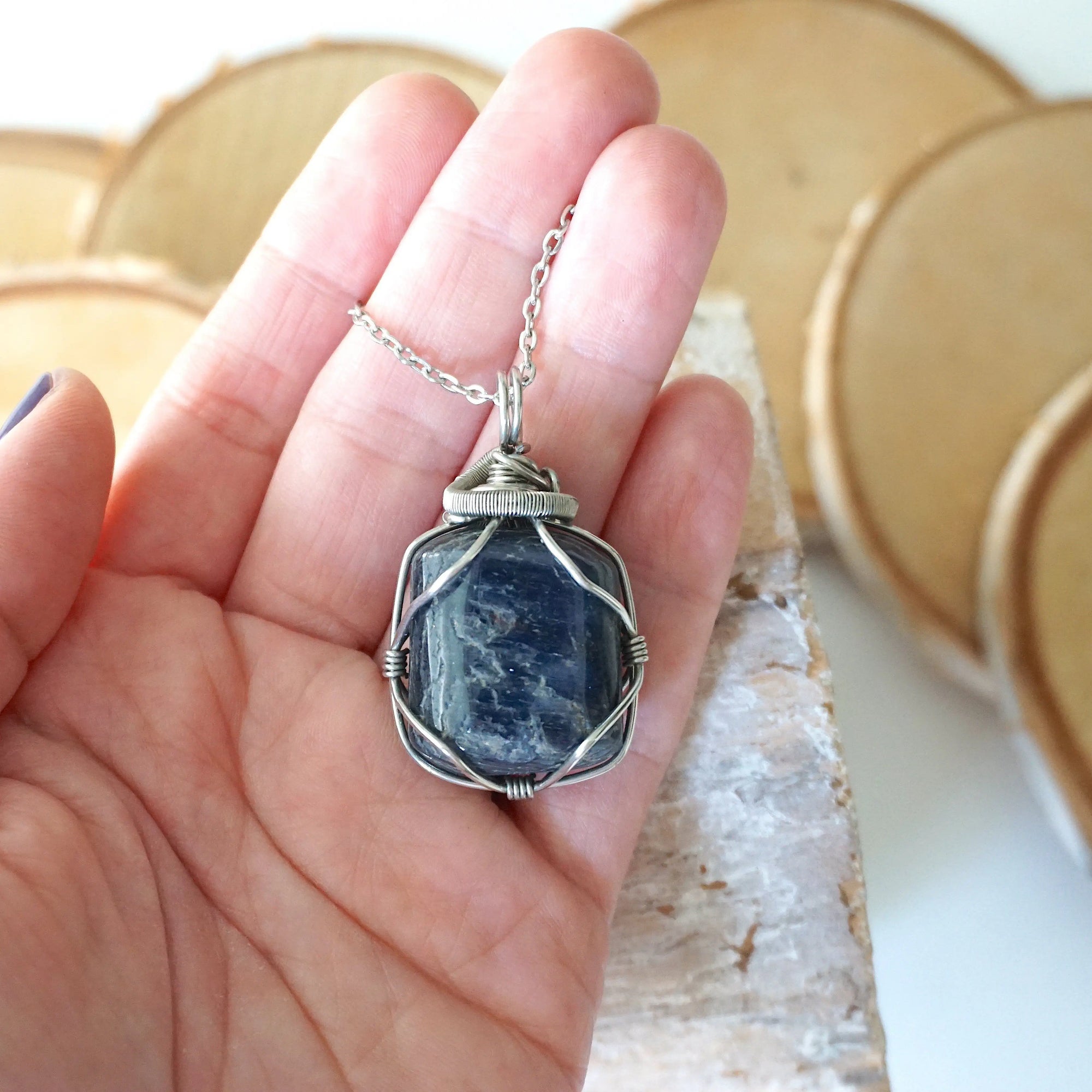 Natural sapphire pendant held in hand to show size — dark silver wire wrap on white gold plated chain, handcrafted crystal necklace by Designs by Nature Gems