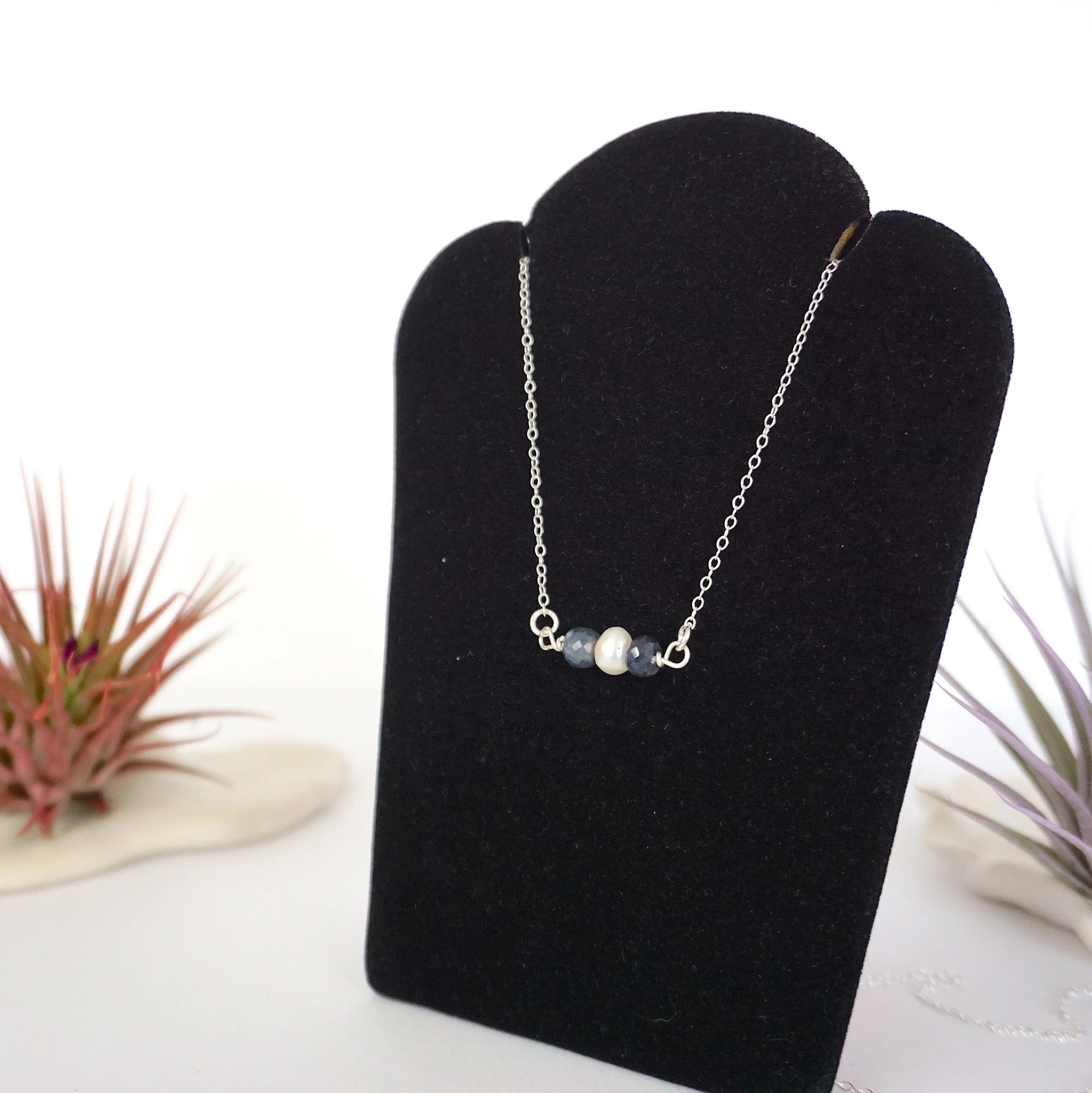 Left angle view of sapphire and pearl bar necklace in 925 sterling silver on jewelry display