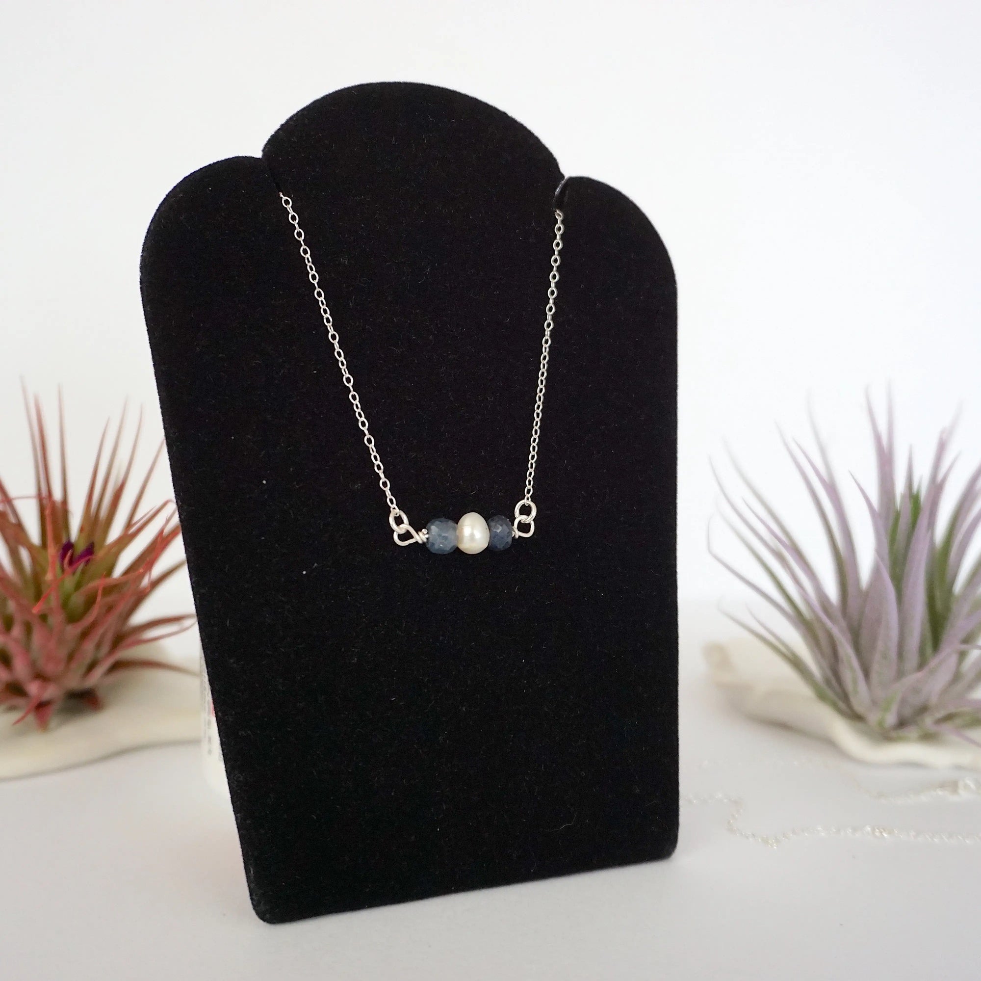 Right angle view of sapphire and freshwater pearl bar necklace in 925 sterling silver on jewelry display
