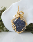 Back angle detail of sapphire and freshwater pearl pendant, showing wire wrapping and natural stone