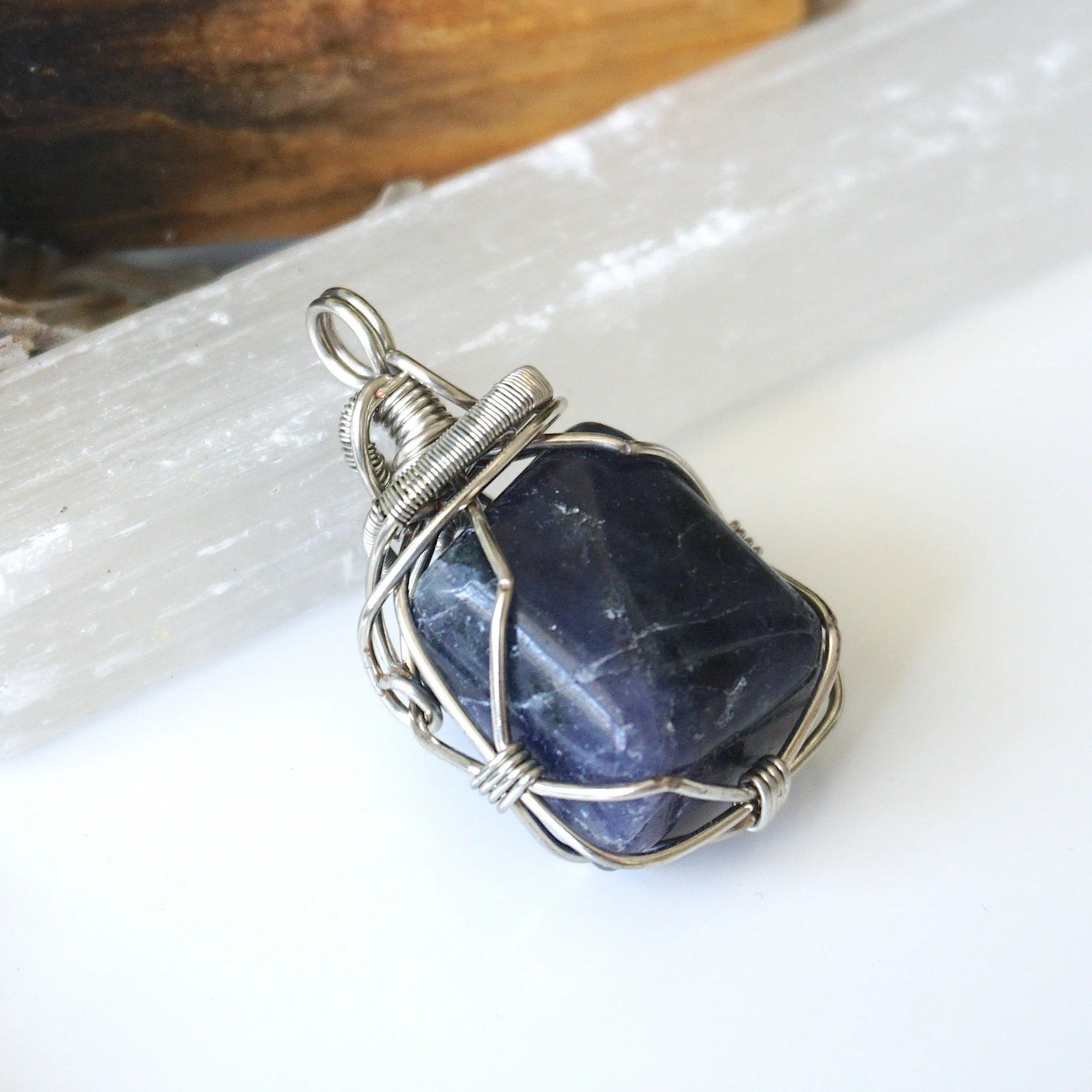 Right-angle detail of natural sapphire pendant showing artisan wire-wrapping in dark silver — handcrafted crystal necklace