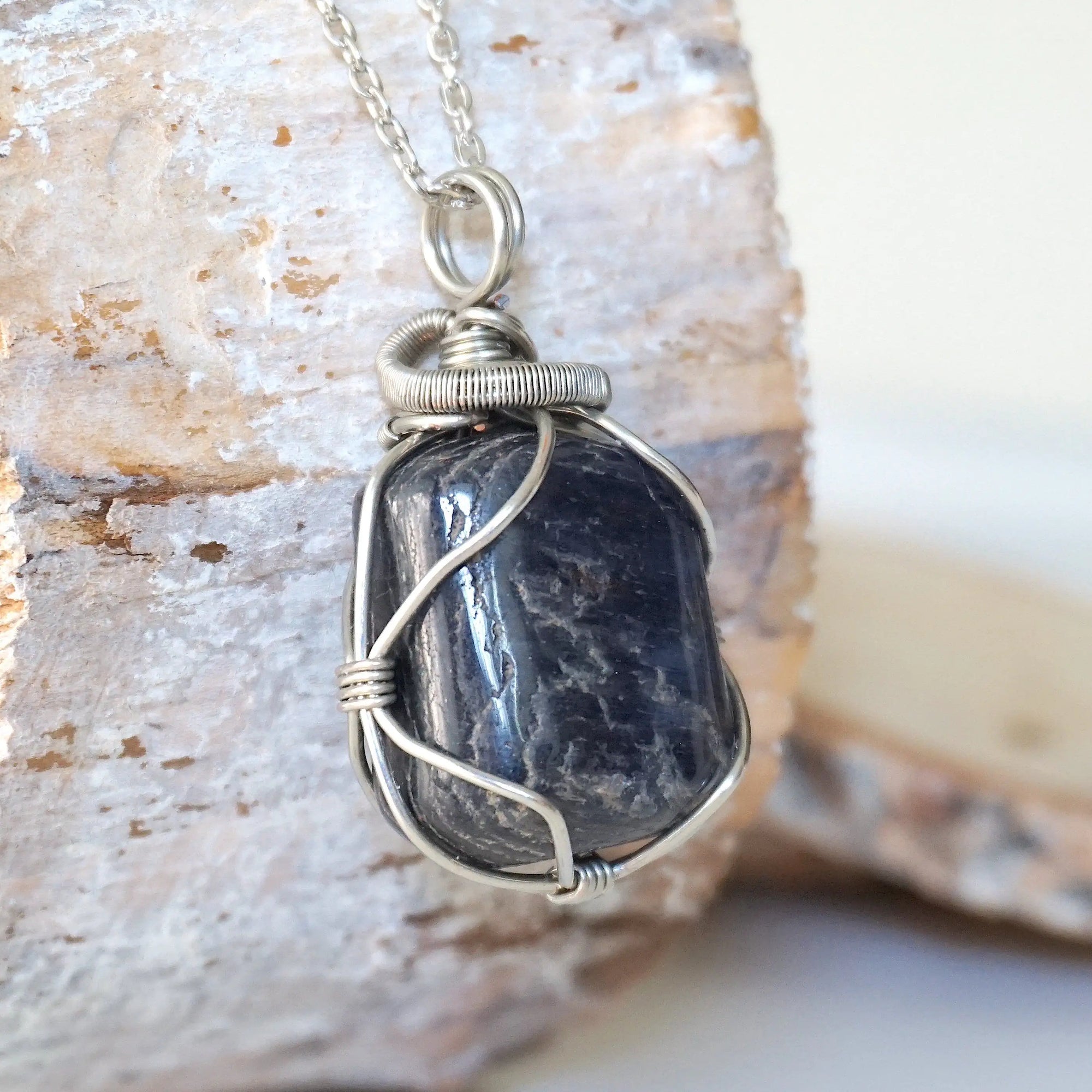 Right-angle detail of natural sapphire pendant showing artisan wire-wrapping in dark silver — white gold plated chain, handcrafted crystal necklace