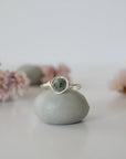Front view of minimalist silver emerald ring with natural faceted emerald bead and artisan wire wrapping.