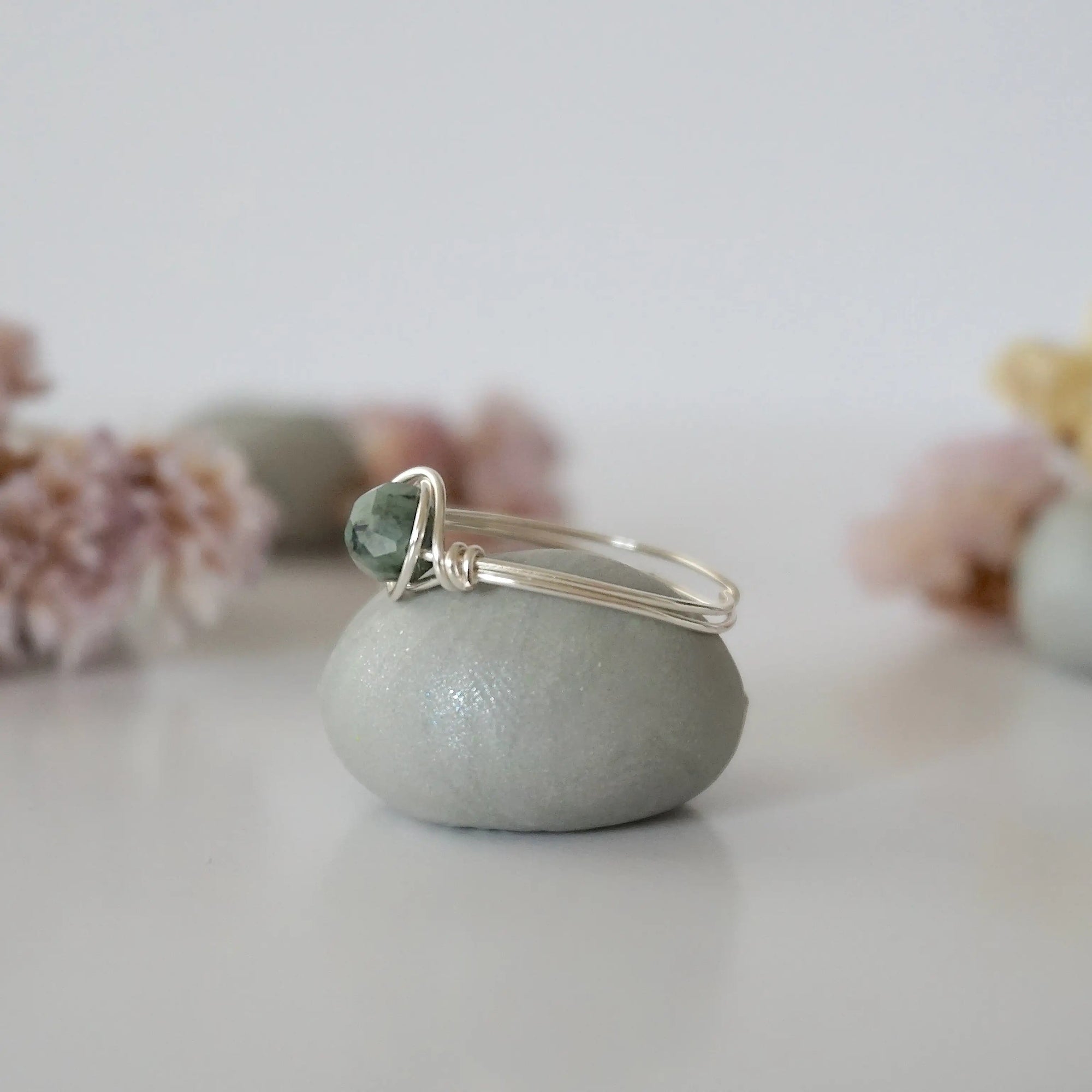 Side view of minimalist silver emerald ring showing classic artisan wire wrapping around a natural emerald bead.