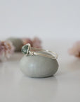 Side view of minimalist silver emerald ring showing classic artisan wire wrapping around a natural emerald bead.