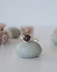 Front detail of minimalist silver wire wrapped garnet ring featuring a single polished garnet bead