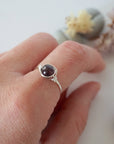 Minimalist garnet bead ring in silver wire wrap on woman’s hand, dainty January birthstone jewelry