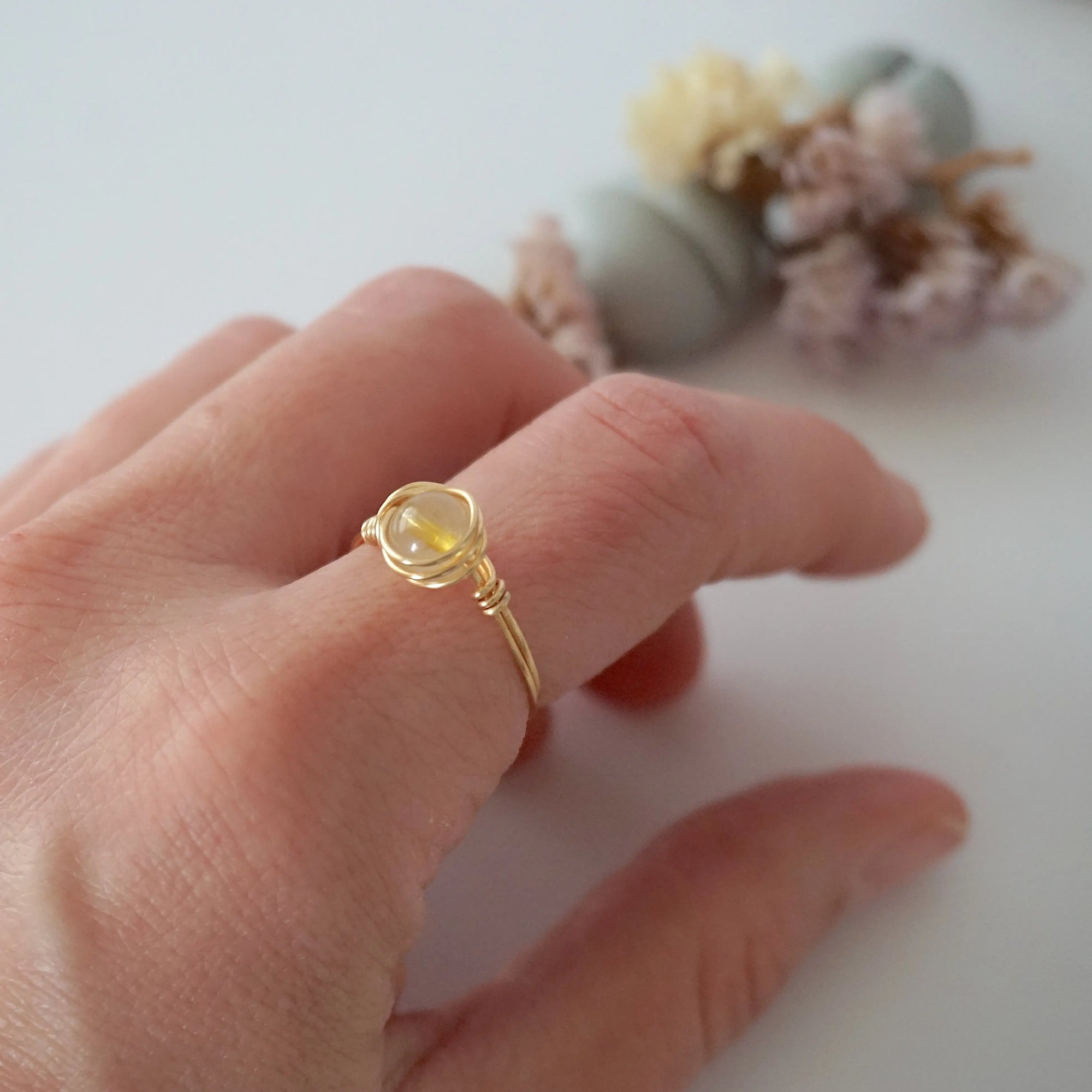 Simple raw citrine ring on woman's hand - minimalist wire wrapped crystal ring in silver showing delicate everyday stacking jewelry for women