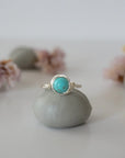 Front view of simple turquoise ring in silver plated copper showing 6mm polished stone and handmade wire wrapping detail