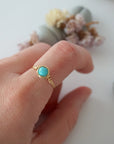Simple turquoise ring for women in gold plated copper worn on hand showing 6mm polished stone and minimalist wire wrap