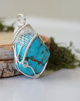 Side angle turquoise pendant showing wire wrap depth and artisan detail
