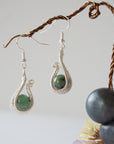 Side angle view of wire wrapped emerald drop earrings in soft silver copper with natural emerald bead and elegant drop shape