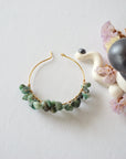 Emerald hoop earrings on flat surface showing classic hoop shape natural emerald chips and handcrafted wire wrapping