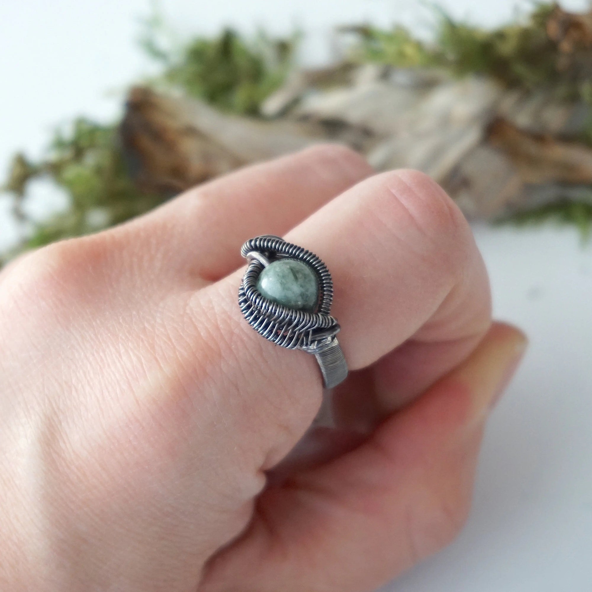 Wire wrapped emerald ring for men in antiqued sterling silver worn on a model's hand
