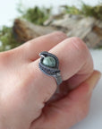 Wire wrapped emerald ring for men in antiqued sterling silver worn on a model's hand