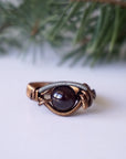 Front angle view of a wire wrapped garnet ring featuring an 8mm garnet crystal bead and mixed metal wire