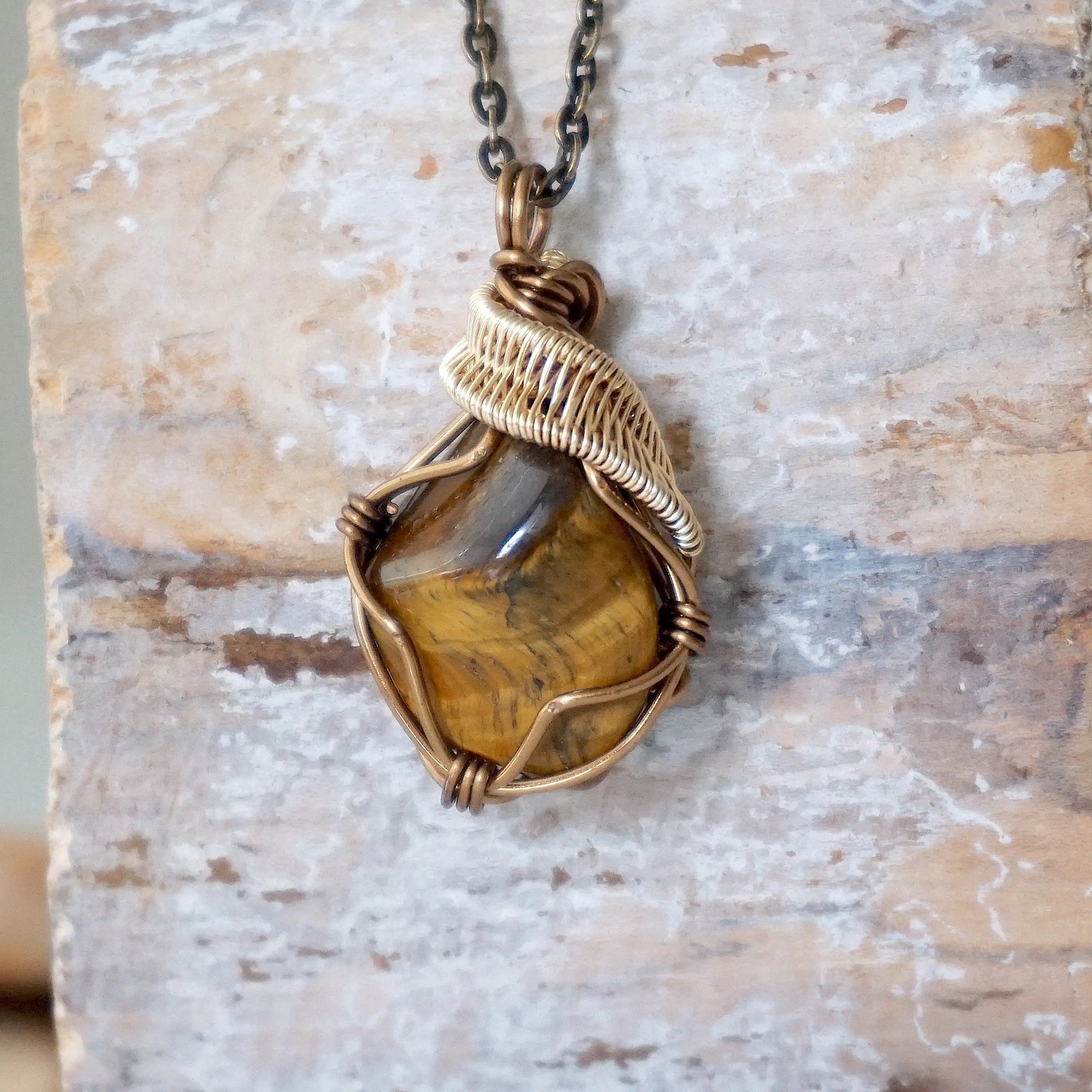Yellow tiger's eye necklace front view — polished-raw stone in antique bronze and gold wire wrap, handmade crystal pendant