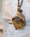 Left side view of yellow tiger's eye pendant showing bronze and gold wire wrapping — handmade crystal necklace for all genders